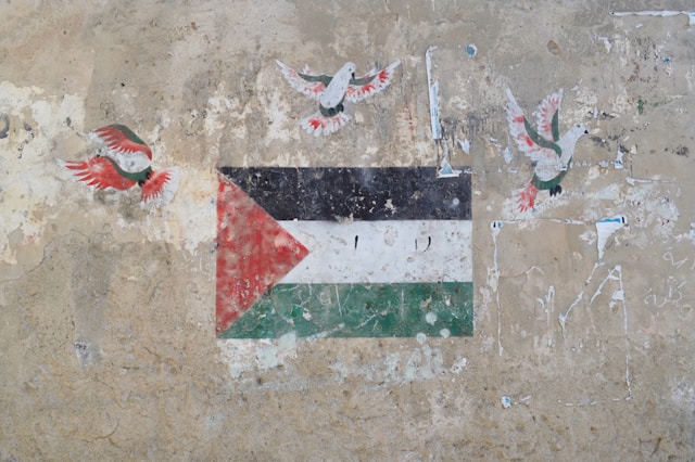 Un grafiti de pombas brancas manchadas de sangue sobrevoando a bandeira palestina