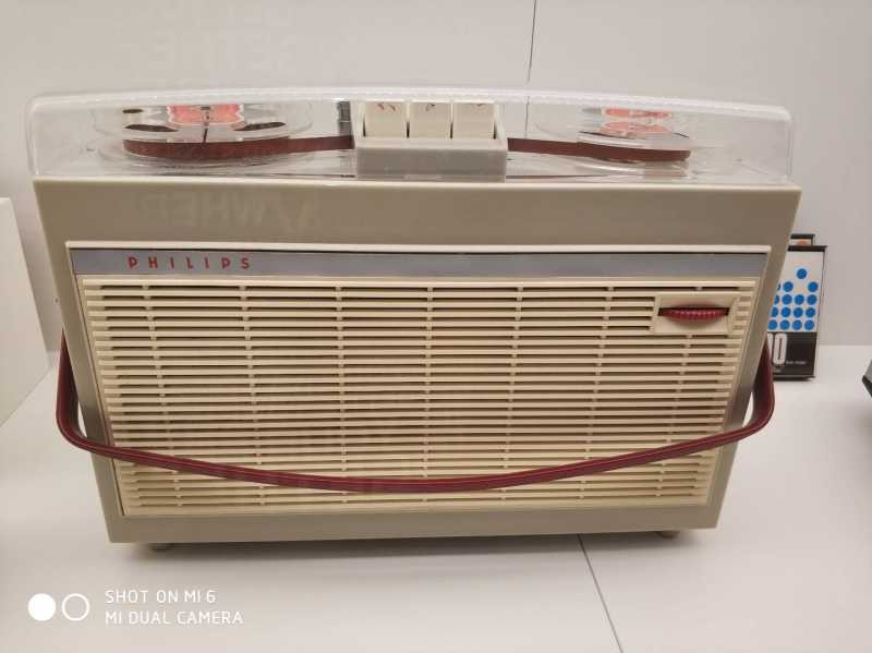 Antiga radio grabadora da marca Philips. É de cor branco con motivos vermellos e grises. Atópase sobre un expositor de museo